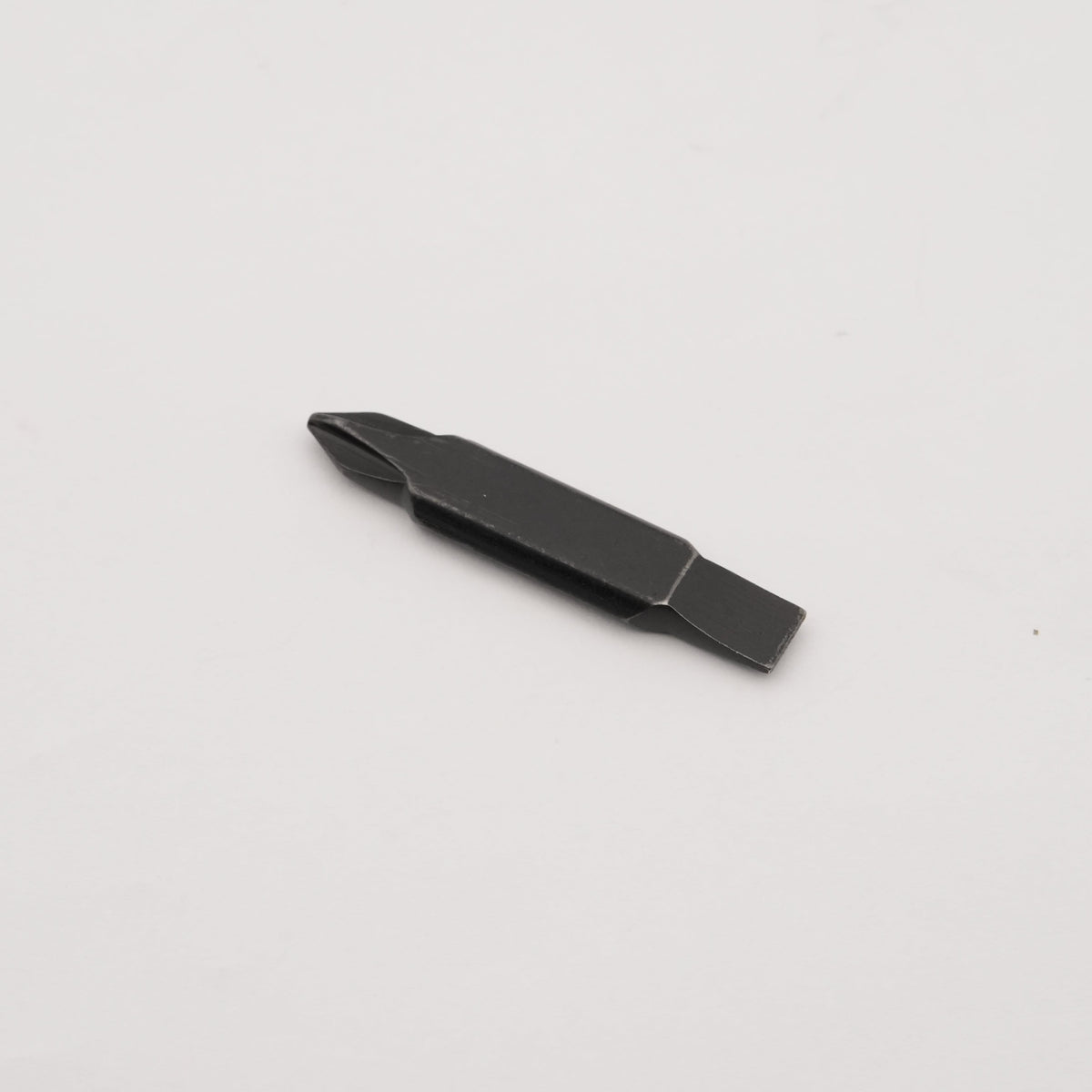A small black flathead screwdriver bit with a slotted center, shown on a plain light gray background.